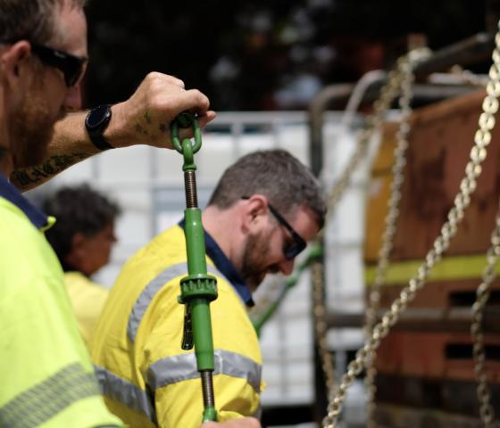 people working on strapping a load down on a truck