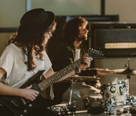 people playing music on electric guitars and drums