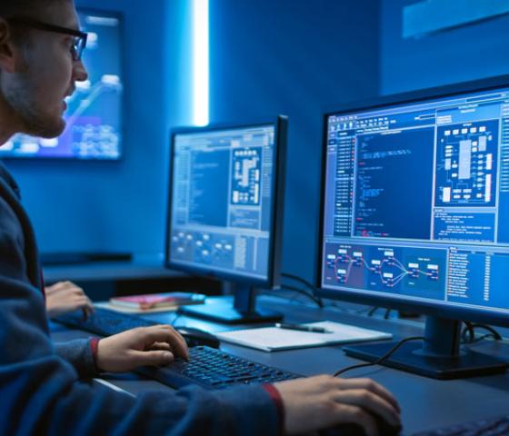 Man at computer with two screens looking at data