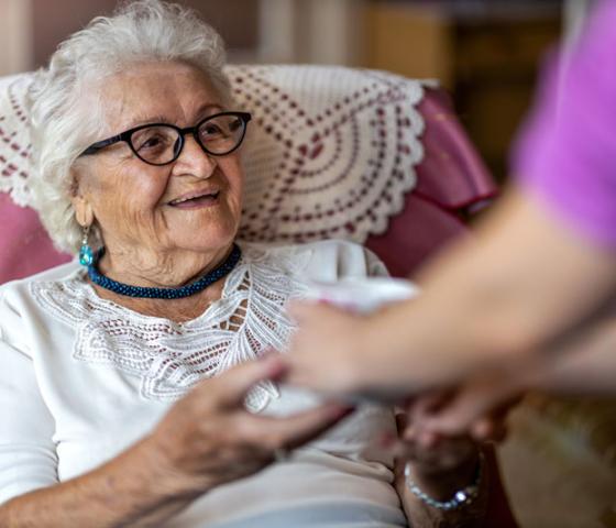 Elderly lady in chair being helped