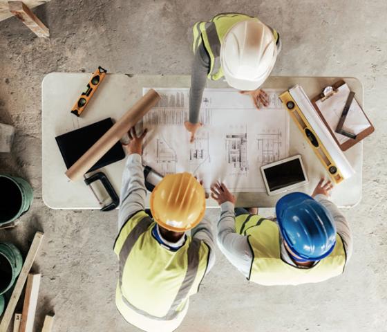 Engineers in a meeting around table with tools and paperwork