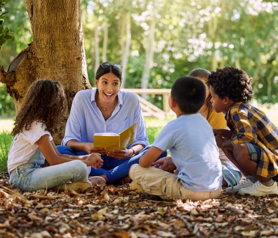 Children with teacher in a circle reading a book