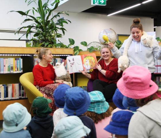 three adults entertaining young children with books and toys