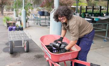 Evan Smith filling soil from a wheelbarrow 